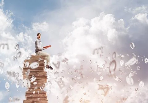 Man student on stack reading book and symbols flying around Foto stock