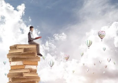 Man student on stack reading book and aerostats flying around Foto stock