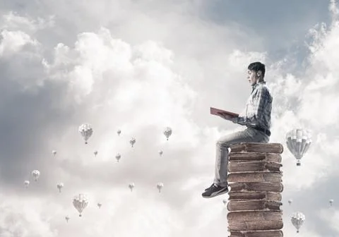 Man student on stack reading book and aerostats flying around Foto stock