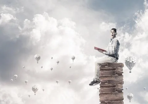 Man student on stack reading book and aerostats flying around Foto stock