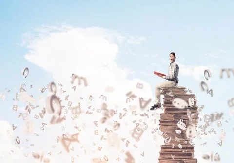 Man student on stack reading book and symbols flying around Foto stock