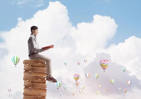 Man student on stack reading book and aerostats flying around Foto stock