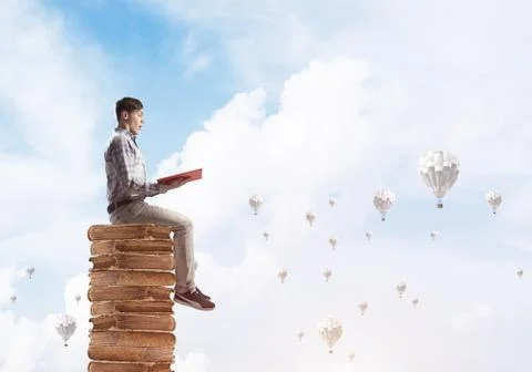 Man student on stack reading book and aerostats flying around 스톡 사진