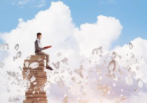 Man student on stack reading book and symbols flying around Foto stock