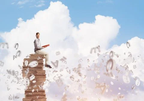 Man student on stack reading book and symbols flying around Foto stock