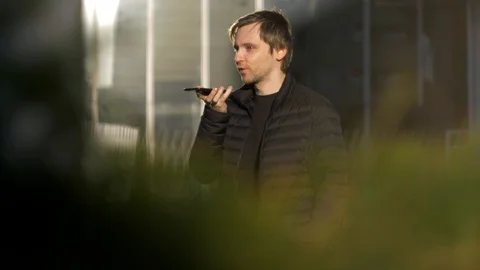 Man student using a smart phone voice recognition function online walking on a Video stock 124232709