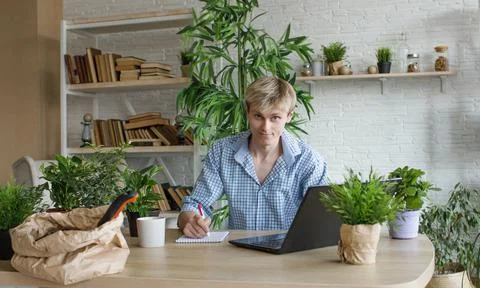A man studies and takes notes with a laptop studying house plants, performs s Stock Photos