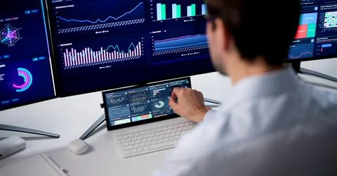 Man Studies Financial Data On Computer Using Smart Analytics Dashboard. Stock Photos