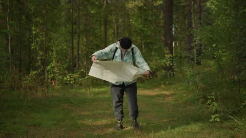 Man studies map, Man analyzes topography using map under forest canopy, Male Stock Footage 333652401