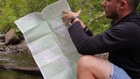Man study the map of the area in a camping near the creek Stock Footage 78643079