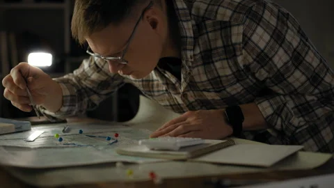 Man studying a map and making notes in a dimly lit room during nighttime Stock Footage 295889887