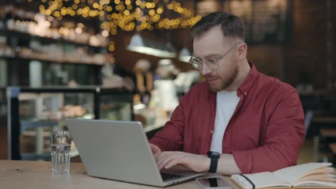 Man studying at the modern cafe, typing on keyboard, while using his laptop. Stock Footage 193054224