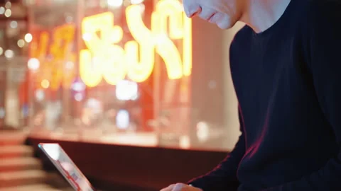 A man in stylish jacket working on laptop in the city at night Stock Footage 252849867