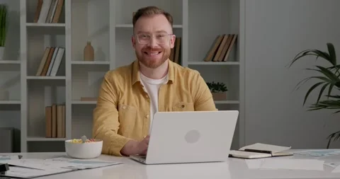 Man in stylish outfit working from office, using laptop, looking at camera. Stock Footage 253990803