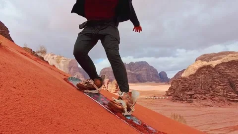 Man successfully sandboarding down steep red dune in Wadi rum showing skill.. Vídeos de archivo 330329624