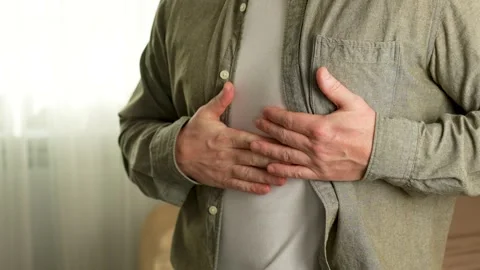 A man with a sudden heartache is sitting on a couch at home Stock Footage 270729902