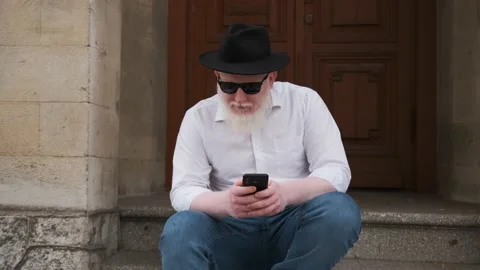 Man suffering from albinism sits outside and surf the internet. Stock Footage 149185094