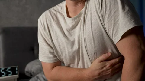 Man suffering from chest pain while sitting on bed at home. Elderly and hea.. Stock Footage 294369429
