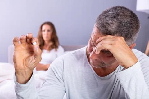 Man Suffering From Erectile Dysfunction Holding Pill In Hand Stock Photos