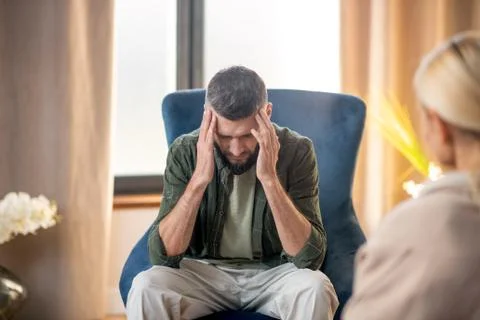 Man suffering from headache while having psychoanalysis Stock Photos