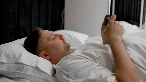 Man suffering from insomnia browsing internet on mobile screen in bed. Stock Footage 340144611