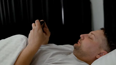 Man suffering from insomnia browsing internet on mobile screen in bed. Stock Footage 340144711