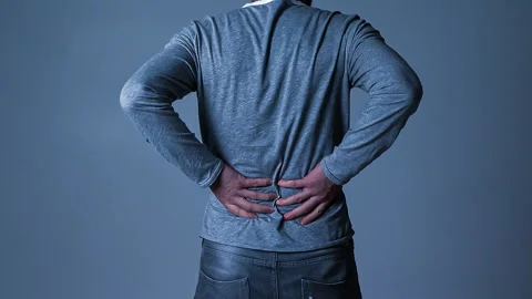 Man suffering from lower back pain, rubbing the area of discomfort for relief Stock Footage 244601128