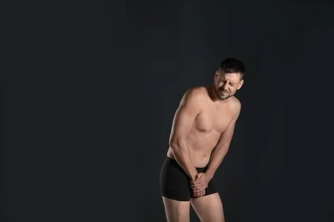 Man suffering from pain on black background, space for text. Urology problems Stock Photos