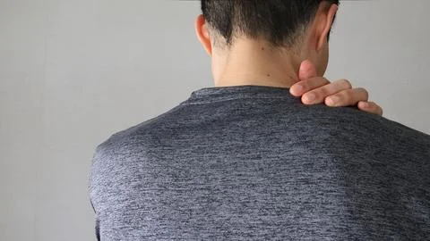 A man suffering from stiff shoulders, seen from behind. Stock Photos