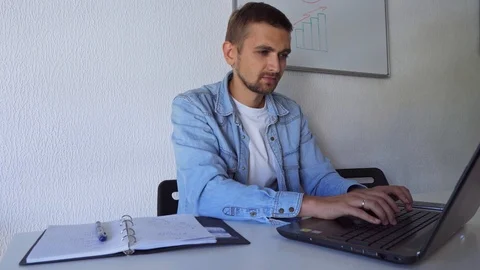 A man suffers headaches while sitting at a laptop. A man massages his temples 스톡 동영상 116602317