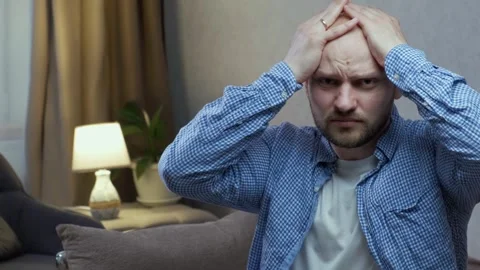 A man suffers from panic attacks, touching his head and looking at the camera Stock Footage 242599461