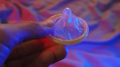 Man suggests using a condom. Colorful atmosphere of the bedroom Stock Footage 295861567