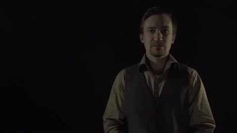 A man in a suit on a black background puts on a gas mask Video stock 130523908