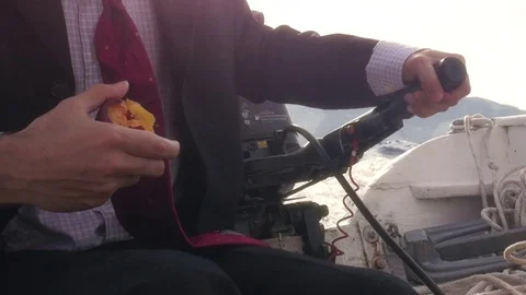 Man in suit with a briefcase eating a peach while driving a boat in the middle Stock Footage 78075271