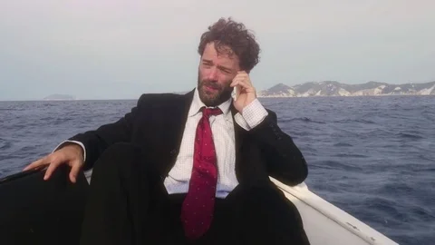 Man in suit with a briefcase talking on his smartphone on a boat in the middle Stock Footage 78036509