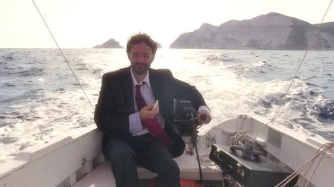 Man in suit with a briefcase texting on his smartphone while driving a boat in 스톡 동영상 78063732