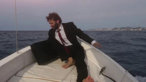 Man in suit with a briefcase touches water from a boat in the middle of the Stock Footage