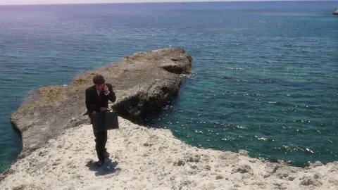 Man in suit with briefcase walking up stone steps while talking on his 스톡 동영상 77737370