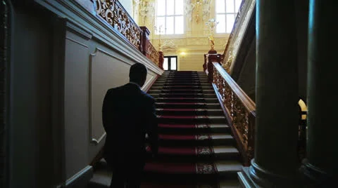 A man in a suit climbing up the stairs to the big hall Stock Footage