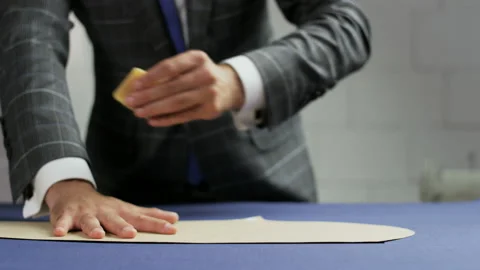 Man in a Suit Drawing a White Line on a Blue Material Stock Footage 88879983