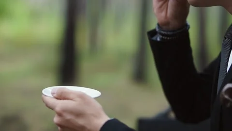 A man in a suit drinks coffee from a small cup Stock Footage 147329329