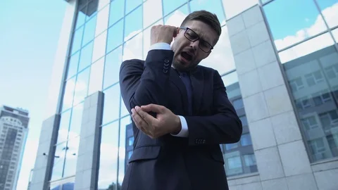 Man in suit feeling acute elbow pain outdoors, joint inflammation, arthritis Stock Footage 119285077
