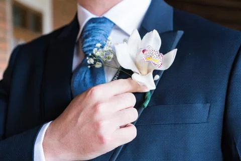 A man in a suit is getting ready for a wedding. He is adjusting his tie and.. Stock Photos