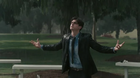 Man in a suit grieving at a funeral while it is heavily raining Stock Footage 262308406