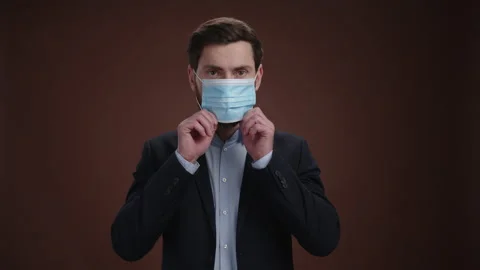 A man in a suit looking at the camera and putting on a protective mask Stock Footage 237215841