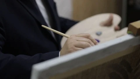 A man in a suit paints on canvas Stock Footage 122965862