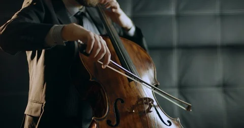 A man in a suit playing a cello in a dark room Stock Footage 87223323