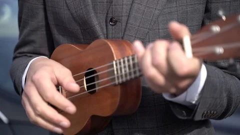 A man in a suit playing the ukulele Stock Footage 103947661