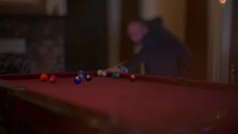 Man in suit plays billiards in a dimly lit room with red felt table Stock Footage 345260613