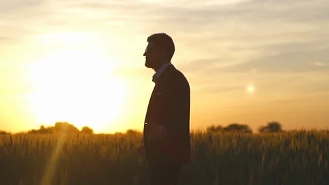 Man in a suit pray in the sunset field  slow motion Stock Footage 76470722